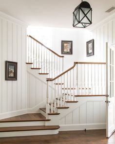 there is a staircase in the house with pictures on the wall and wood flooring