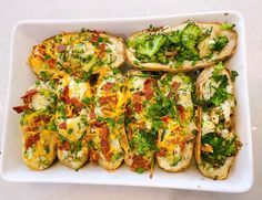 baked potatoes with broccoli, cheese and other toppings in a white dish