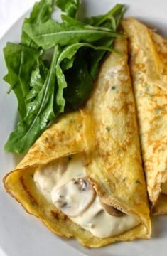 two quesadillas on a white plate with spinach leaves and cheese sauce