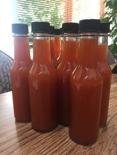 six jars filled with liquid sitting on top of a wooden table