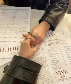 two people holding hands over papers on a table