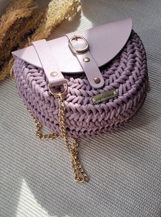 a crocheted purse with a chain hanging off the side and a leather handle