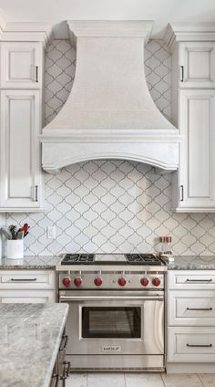 a stove top oven sitting inside of a kitchen next to white cabinets and counter tops