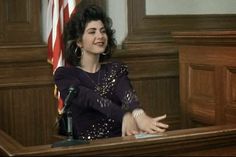 a woman sitting at a desk with her hands out and an american flag in the background