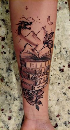 a tattoo on the leg of a person with a book and roses in it,