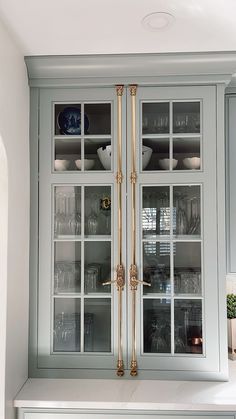 a kitchen cabinet with glass doors and gold trimmings on the front, in an otherwise white color