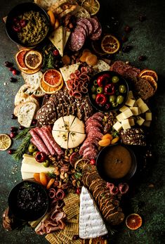 an assortment of cheeses, meats and other foods are arranged on a platter