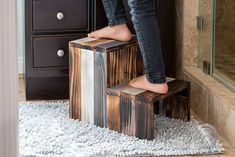 a person standing on a stool made out of wood blocks in front of a dresser