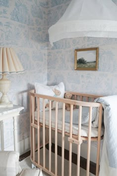 a baby's crib in the corner of a room with blue and white wallpaper