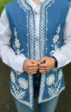 Step up your style with this Victorian-inspired embroidered waistcoat, crafted in a soft denim outer shell in a beautiful sky blue hue. The inner lining is made from premium quality butter crepe, offering a luxurious feel against the skin. The intricate handmade embroidery, created with cotton-linen thread, adds a unique and artisanal touch to this elegant piece. This versatile waistcoat is perfect for casual wear with jeans or trousers and makes a striking statement at any special occasion. Whe Luxury Blue Cotton Vest, Luxury Blue Summer Vest, Embroidered Waistcoat, Denim Waistcoat, Linen Thread, Handmade Embroidery, Vest Outfits, Beautiful Sky, Blue Hues