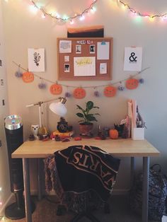 a desk with halloween decorations on it and lights strung over the wall in front of it