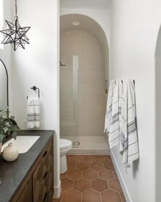 a bathroom with white walls and brown tile flooring next to a walk in shower