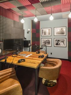 a room with two chairs, a table and speakers on the wall in front of it