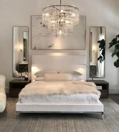 a bedroom with a bed, mirror and chandelier