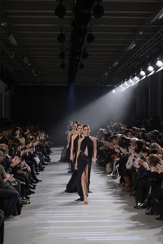 two models walk down the runway in black dresses