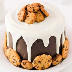 a cake with chocolate chip cookies and white icing on top is sitting on a plate