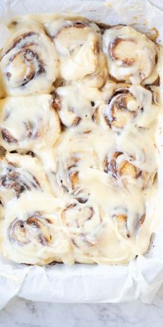 a pan filled with cinnamon rolls covered in white icing