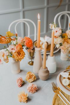 the table is set with candles and flowers in vases, plates and napkins