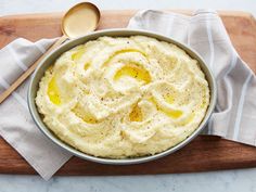 a bowl filled with mashed potatoes sitting on top of a wooden table next to a spoon