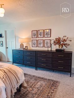 a bedroom with a bed, dresser and pictures on the wall