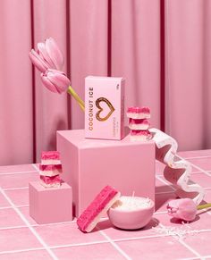 a pink table with some pieces of cake on it and a flower in the middle