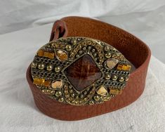 "You are looking at a genuine leather belt by Leatherock USA. Belt is size medium to large and measures 38\" long, 1\"2 wide, with 28\" 4 from the first perforation and 32\"4 at it's last perforation. Buckle measures 3\"1 wide X 2\"2 at it's highest. There are a few light scuffs with no tears. The condition of this belt is good with great detail, brass tone hardware with several stones and rhinestones. 100% genuine Leatherock made in USA. I want to stress that item is vintage which means it's no Brown Leather Belt With Antique Buckle, Brown Artisan Belt With Antique Buckle, Southwestern Brown Belt With Antique Buckle, Vintage Brown Belt With Brass Buckle, Vintage Brown Belts With Rivets, Tan Leather Belt, Genuine Leather Belt, Shopping Tote Bag, Black And Tan