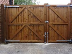 a large wooden gate with metal bars on it's sides in front of a brick building