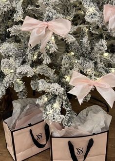 two bags with bows are sitting next to a christmas tree