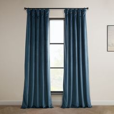 a blue curtain hanging in front of a window next to a framed painting on the wall