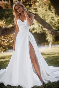 a woman in a white wedding dress posing for the camera with her leg slit open