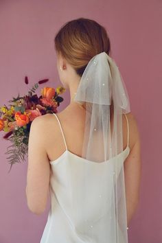 a woman wearing a veil and holding a bouquet of flowers in front of her face