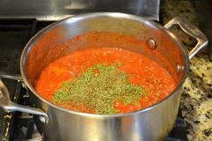 a pot filled with red sauce and spices on top of a stovetop next to a burner