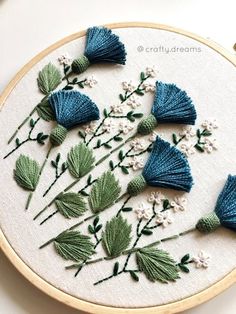 a close up of a embroidery on a hoop with flowers and leaves in the middle