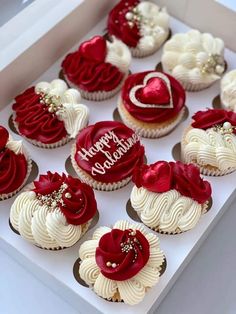 a box filled with cupcakes covered in white frosting and red icing