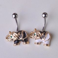 two gold and white elephant belly rings with green stones on each one side, sitting next to each other