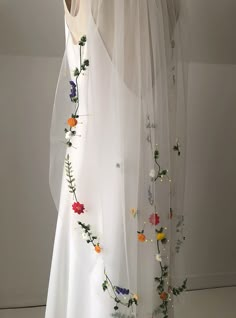 a white veil with flowers on it hanging from the ceiling in front of a window