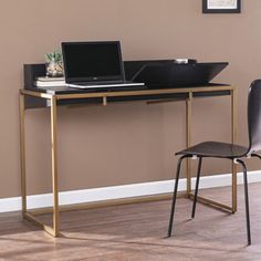 a laptop computer sitting on top of a wooden desk next to a black chair in front of a brown wall