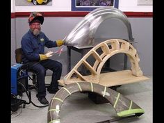 a man sitting on a bench made out of plywood and metal parts in a garage