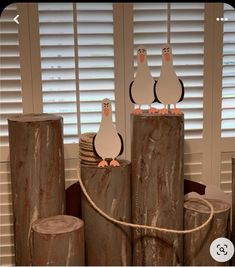 three penguins are sitting on top of logs and tied to each other in front of the window