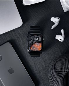 an apple watch sitting on top of a table next to ear buds and headphones