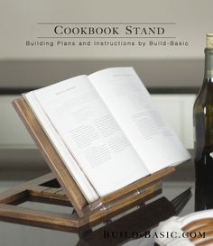 an open book sitting on top of a wooden stand next to a bottle of wine