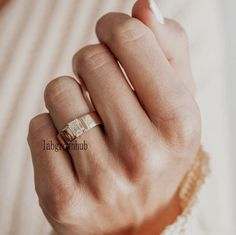 a woman's hand with a gold ring on her left wrist, wearing a white sweater