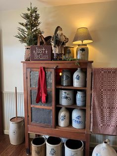 a shelf filled with lots of different types of vases and containers next to a christmas tree