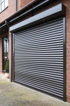 a closed garage door on the side of a brick building