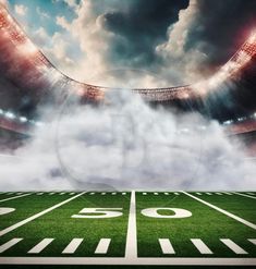 an empty football field with clouds in the sky and stadium lights on it's sides