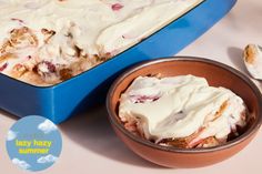 a blue casserole dish with white icing next to a bowl of fruit