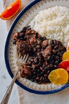 a plate filled with rice, beans and orange slices