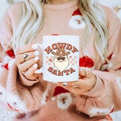 a woman holding a coffee mug with the words hodgy santa on it in front of her face