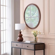 a table with a mirror and vase on it