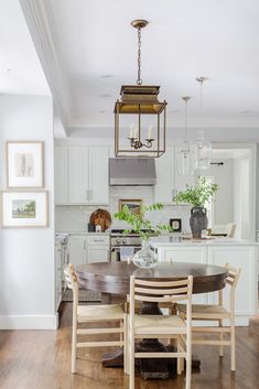 a dining room table and chairs in front of a kitchen with white cabinets, wood floors and an island